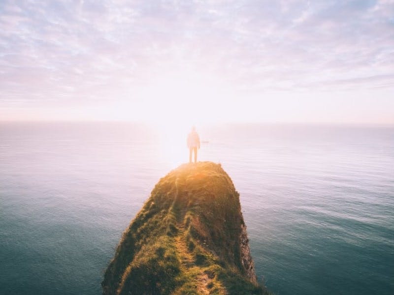 person standing on edge of cliff ocean 15 Benefits of Marijuana That Can Improve Your Life