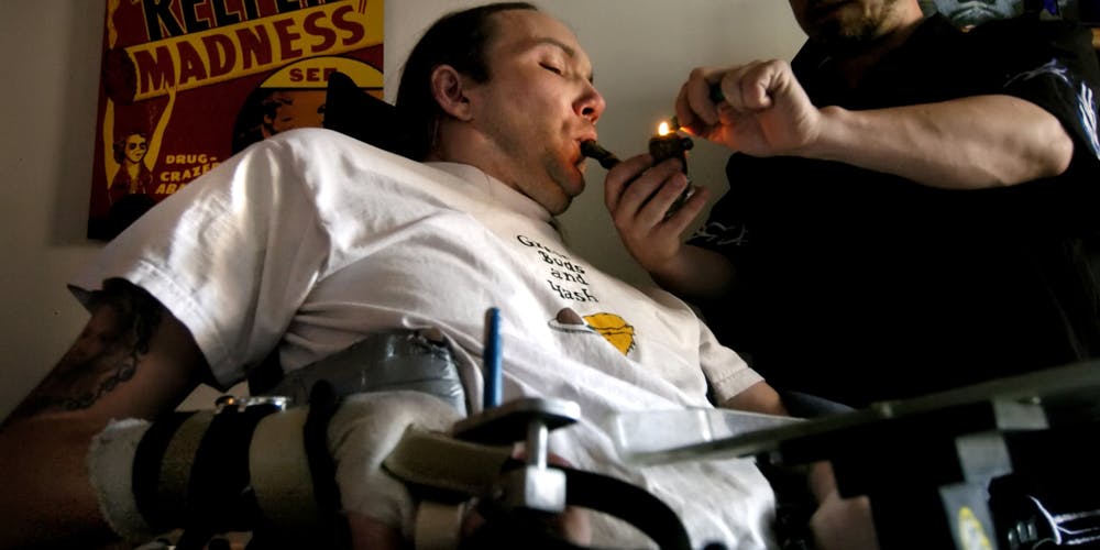 DENVER, CO, JUNE, 6, 2005 - Micah Moffett, a quadriplegic confined to a wheelchair since a motorcycle accident in 1991, needs assistance from his licensed marijuana caregiver, Jay Buzzalini to help administer his medical dose. Buzzalin