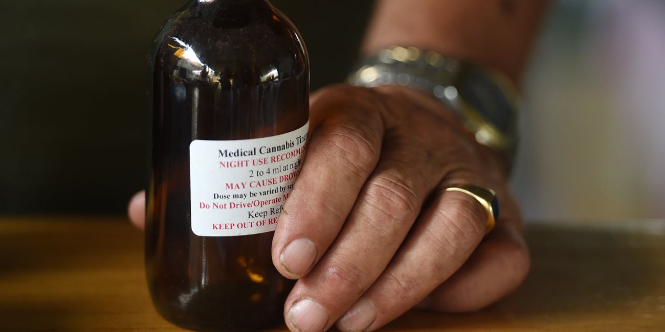Hand holding a bottle of medical cannabis oil