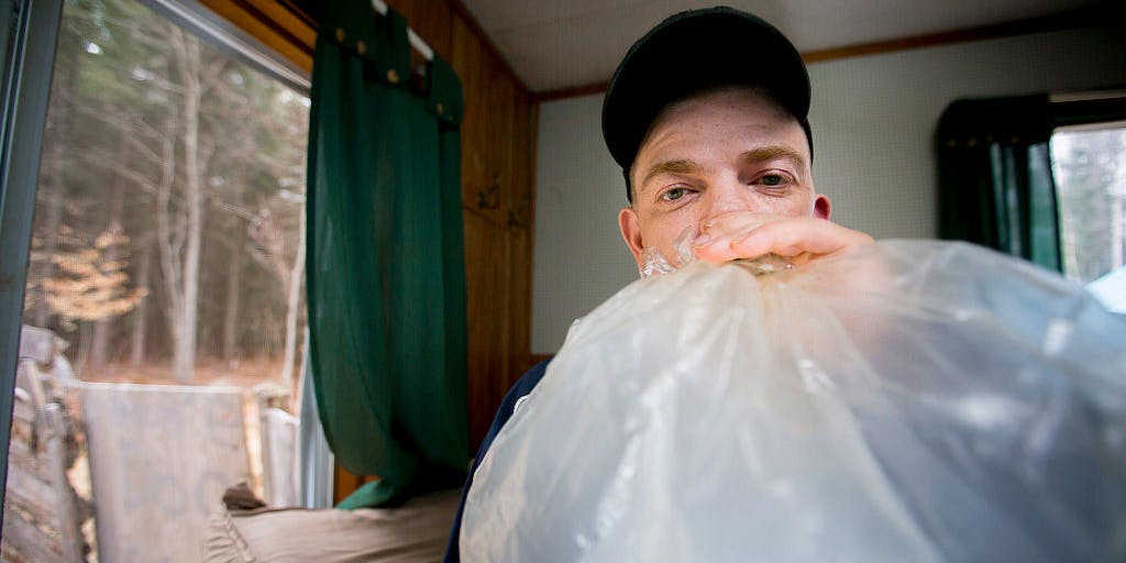 Man smoking medical marijuana vapor from a plastic bag in his home.