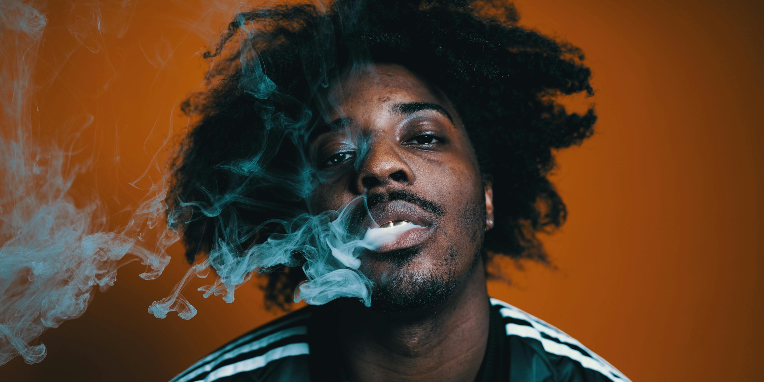 Sean Leon blows out a milky cloud of marijuana smoke