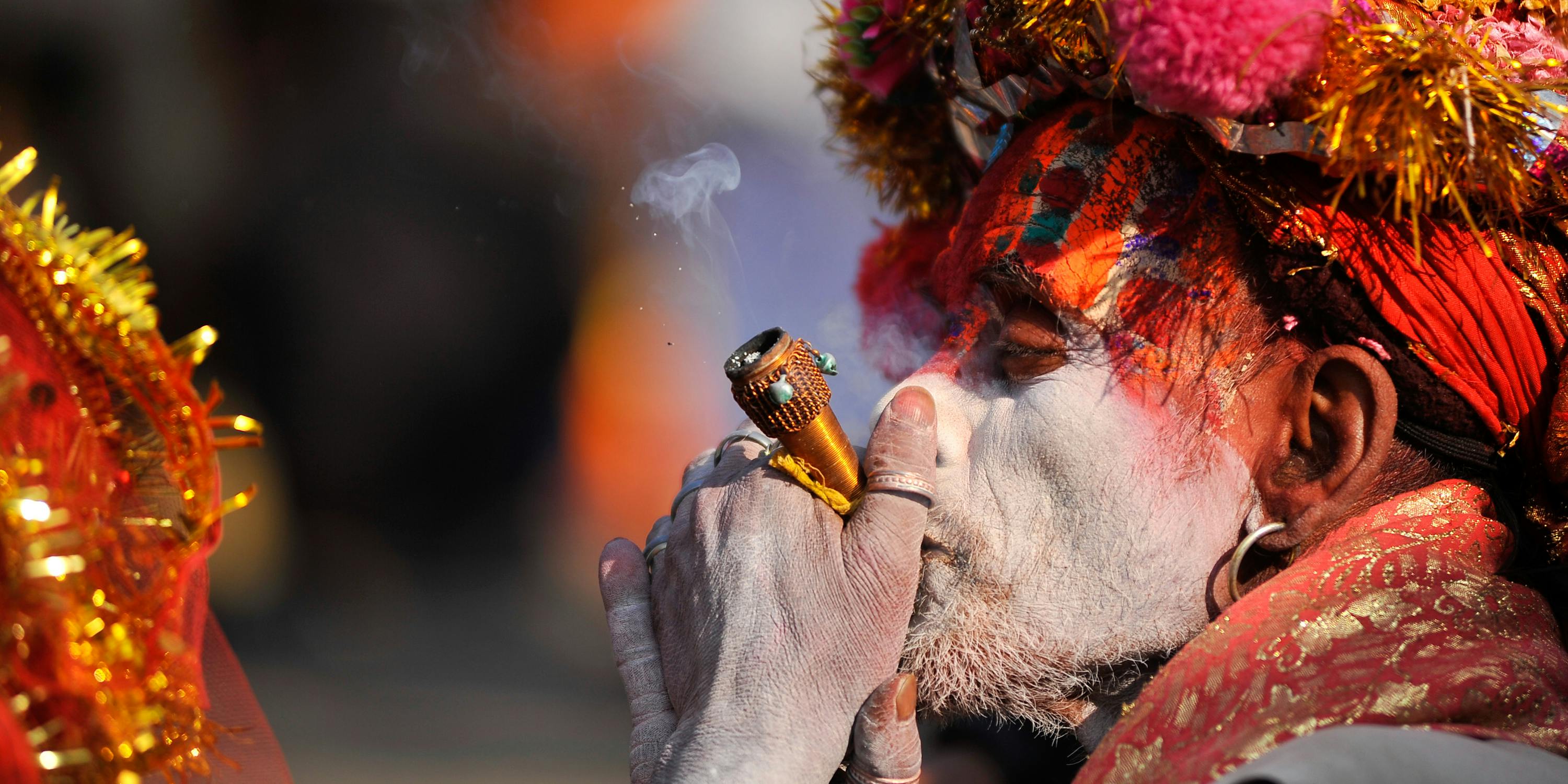 A colorful Hindu Sadhu or Holy Man smokes marijuana at the