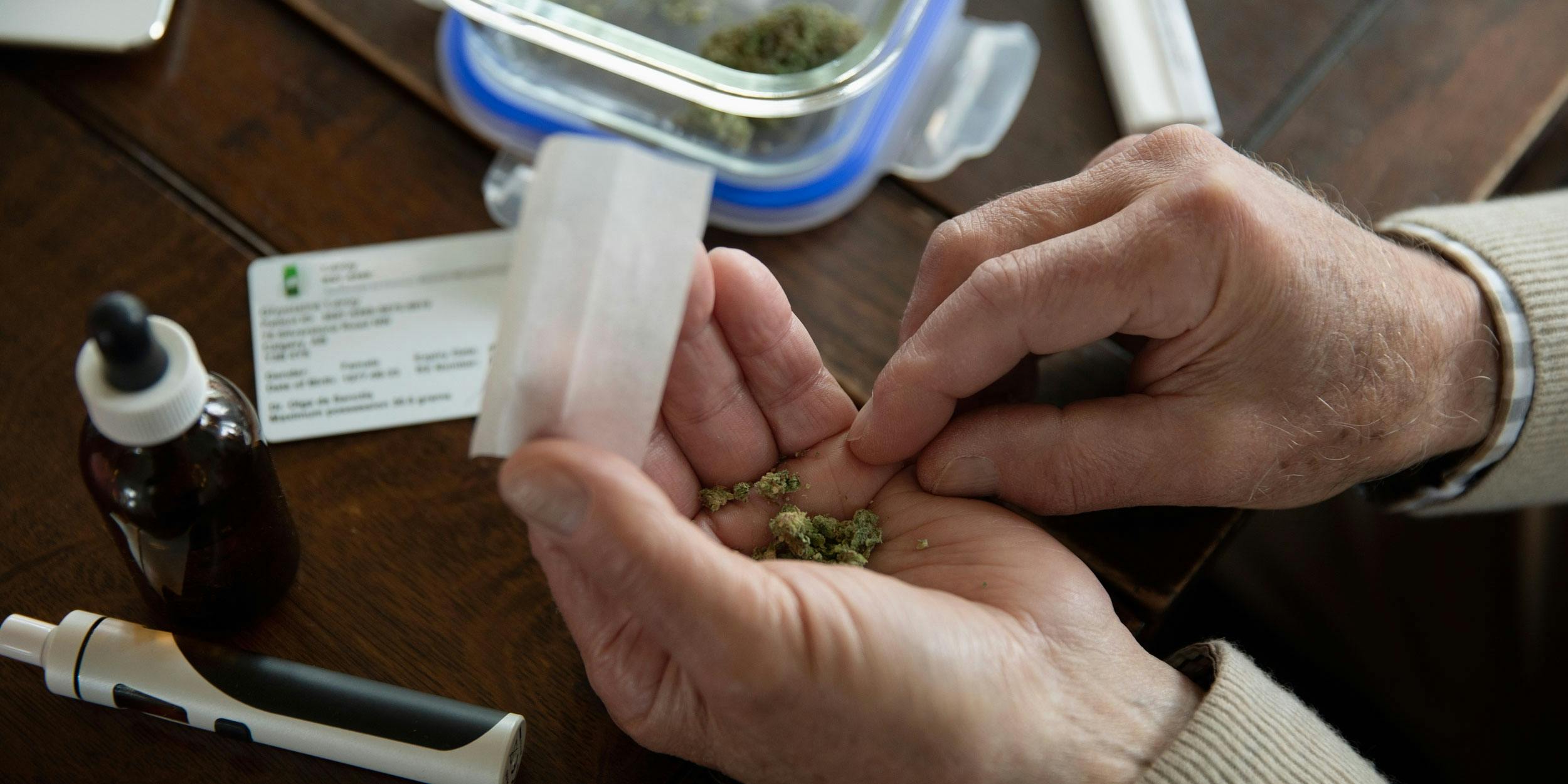 Medical Marijuana in an old mans hands next to cbd oil and a vaporizer