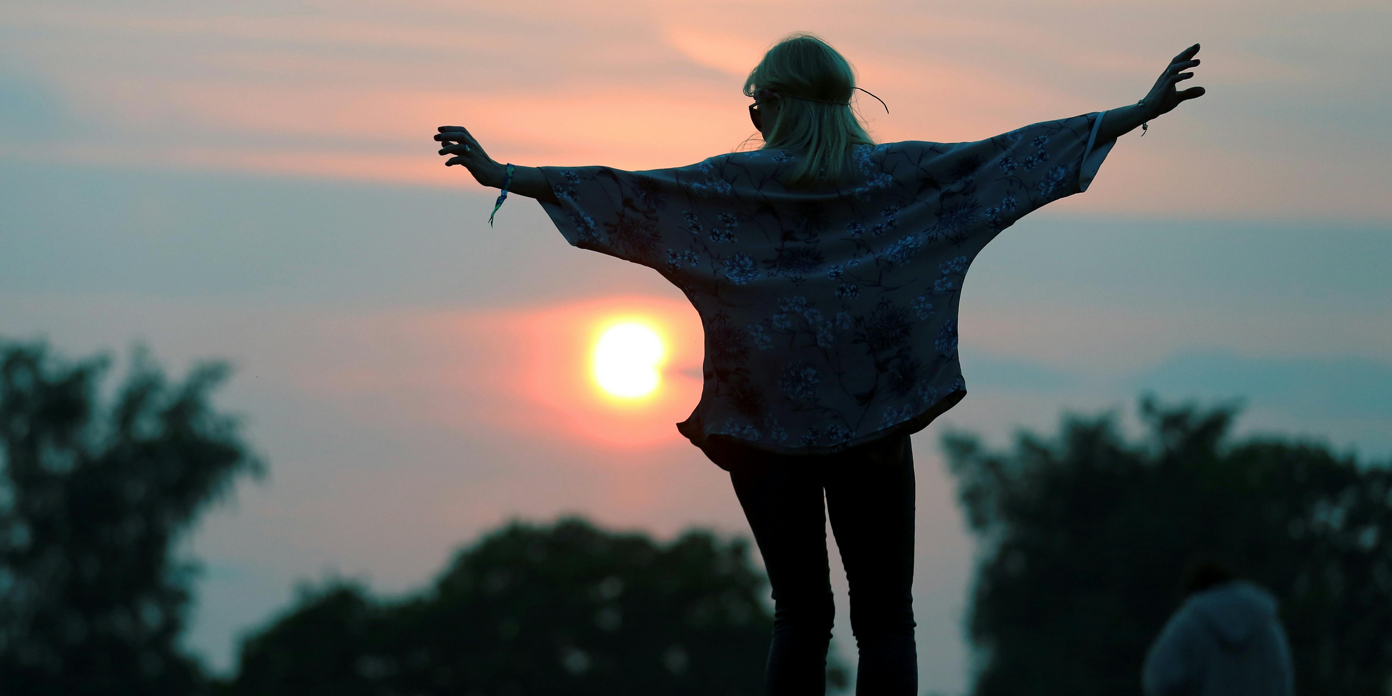 GLASTONBURY, ENGLAND - JUNE 26: A woman stands on a rock at the stone circle as people gather for sunset at the Glastonbury Festival of Contemporary Performing Arts site at Worthy Farm, Pilton on June 26, 2013 near Glastonbury, England. Northern Nights in the Emerald Triangle just announced major discounts for attendees who buy the local weed