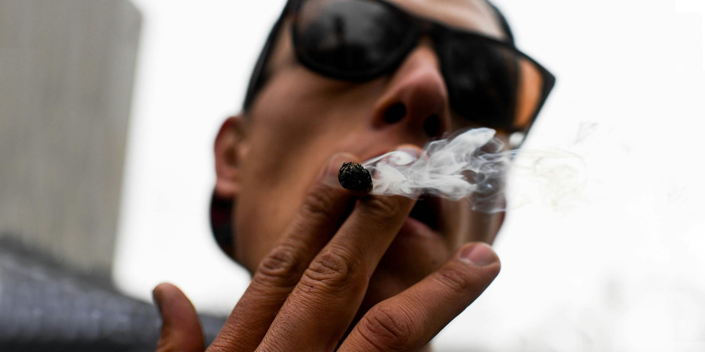 A man smokes a blunt while wearing glasses. Statistics show that cannabis use disorder is a real thing, and numbers are soaring.