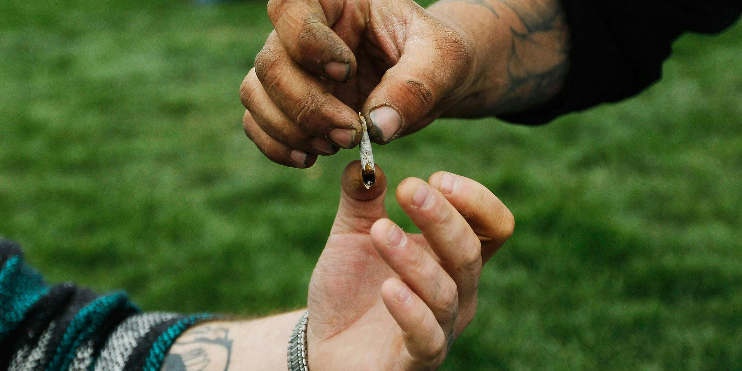 Men pass a marijuana cigarette to each other during a pro-marijuana rally at Civic Center Park with the Colorado State Capitol Building in the background on April 20, 2010 in Denver, Colorado. The DEA just updated its list of drug slang, which includes terms for weed like "pink panther."