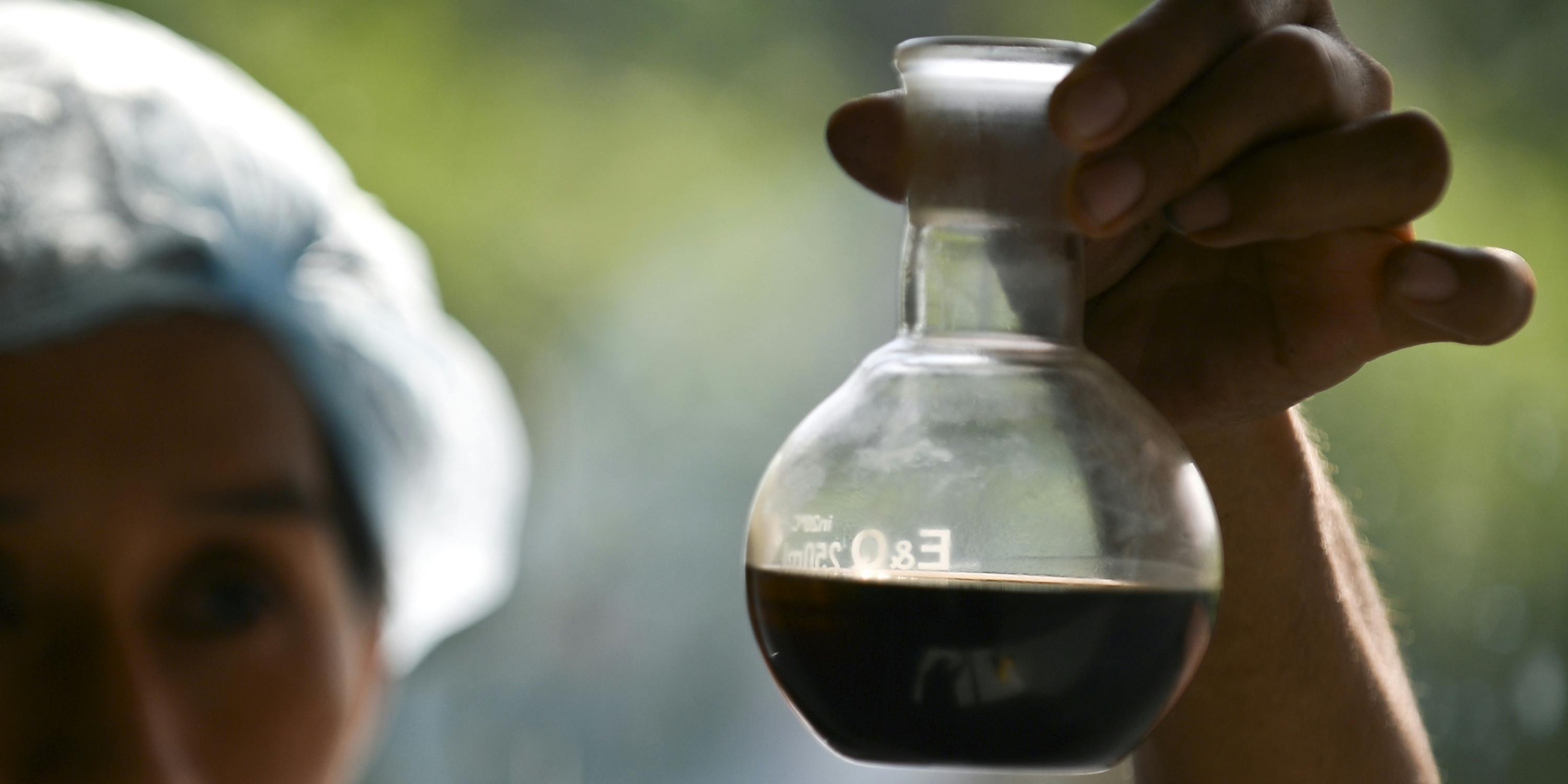 A Colombian indigenous woman observes liquid extract of marijuana at the laboratory of Toez indigenous reservation, in the rural area of Caloto, department of Cauca, Colombia, on May 23, 2016. In Oklahoma, and other states, there's been debate over whether patients need access to high potency cannabis products or whether a THC limit is in the best interest of the public. (Photo by Luis Robayo/AFP via Getty Images)