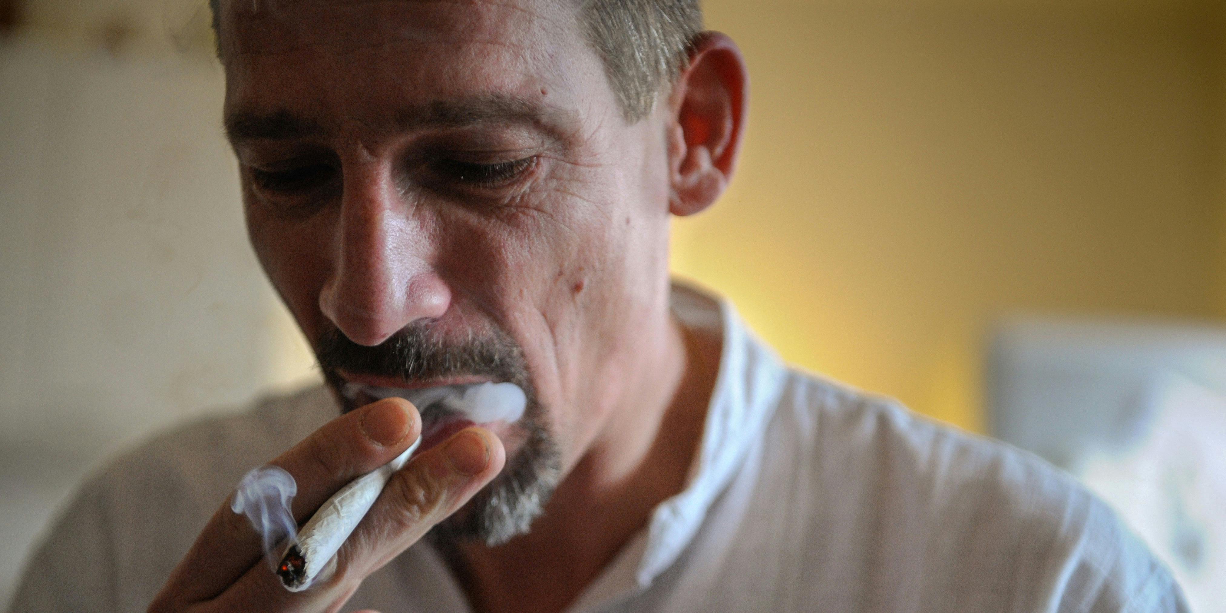 Dominique Loumachi, suffering from Dermatomyositis (Myopathy), smokes a cigarette that looks like a cannabis cigarette in order not to be charged for promoting consumption of narcotic substances while posing on February 28, 2013 in Belfort, Eastern France. Rhode Island dispensaries recently announced that they would recognize out-of-state medical marijuana licenses.