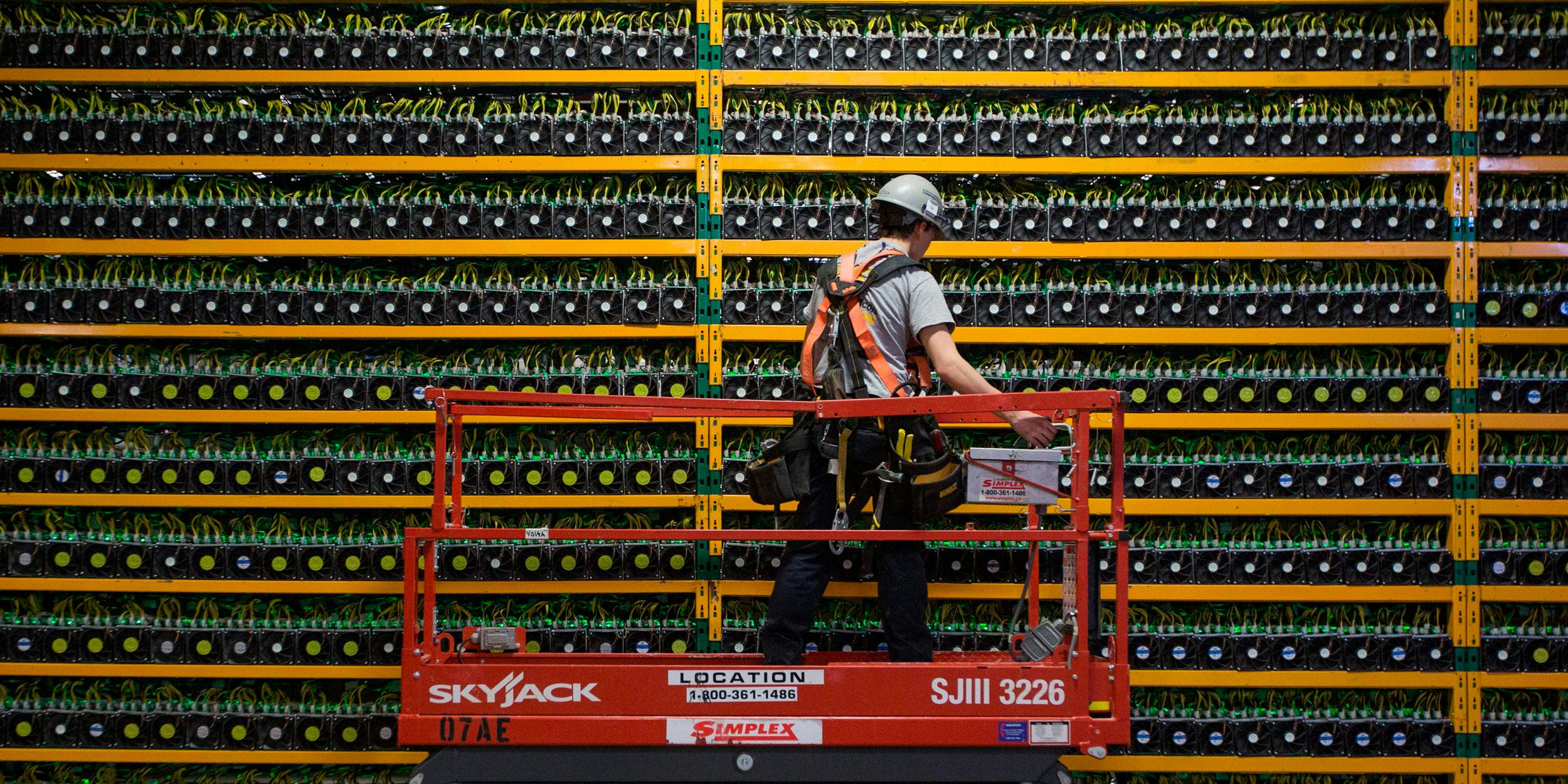 A technician inspects the backside of Bitcoin mining at Bitfarms in Saint Hyacinthe, Quebec on March 19, 2018. Bitcoin is a cryptocurrency and worldwide payment system. It is the first decentralized digital currency, as the system works based on the Blockchain technology without a central bank or single administrator. (Photo by Lars Hagberg /AFP/Getty Images)