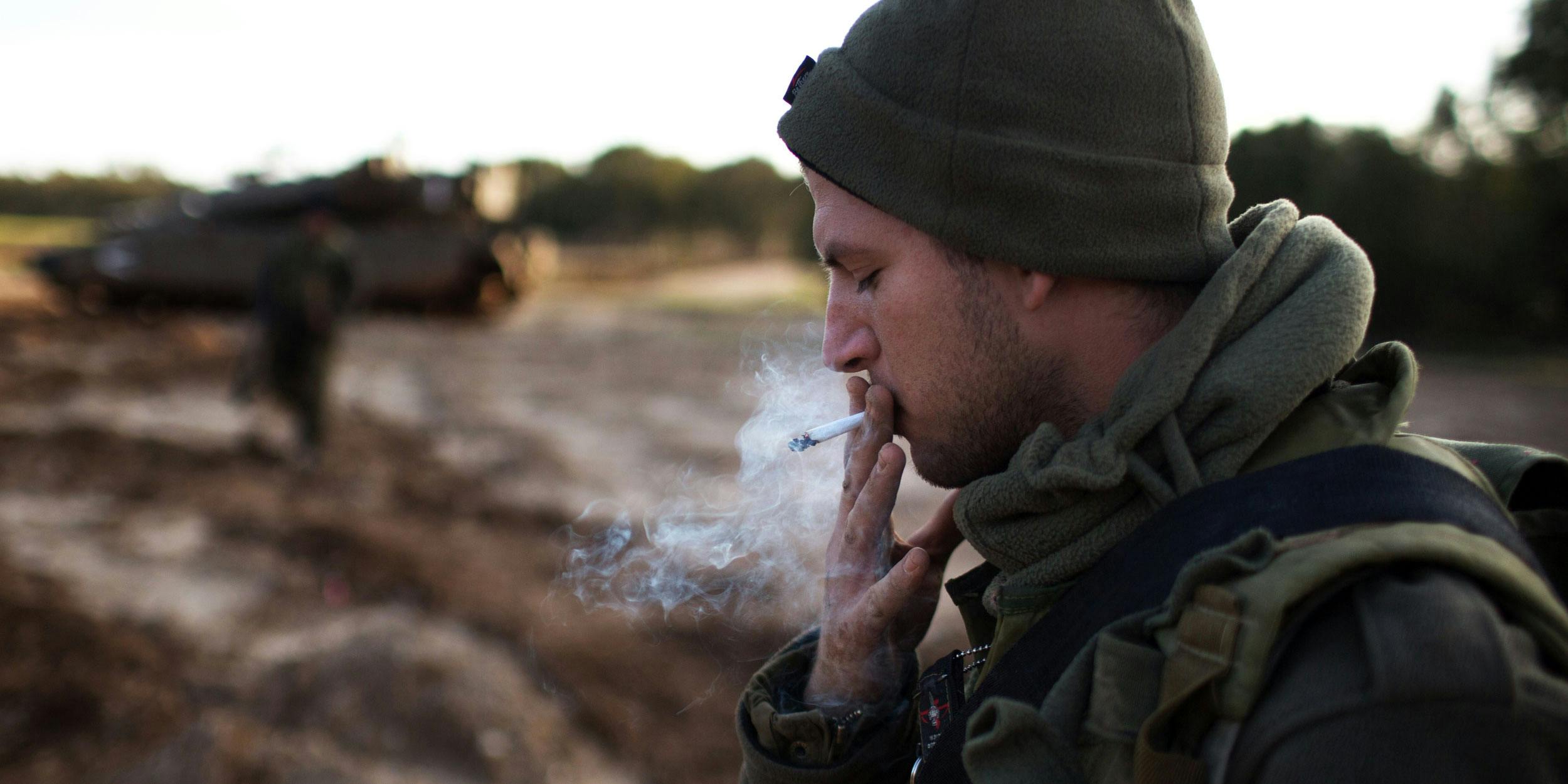 An Israeli soldier smokes a cigarette next to his Merkava tank positioned along the southern border with the Gaza Strip on December 25, 2013. Many Israelis smoke cannabis to cope with the trauma of growing up in a war torn country. (Photo by Mehahem Kahana/AFP/Getty Images)