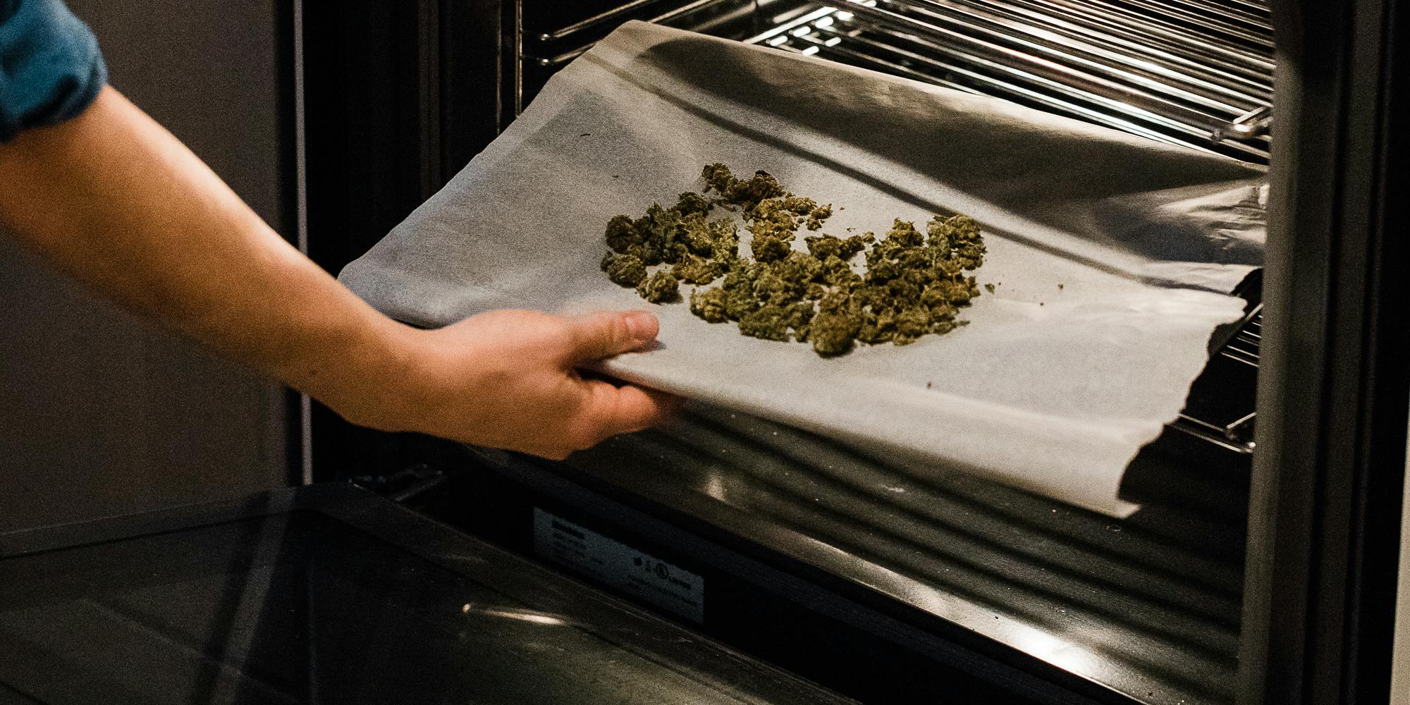 Cannabis flower on a cooking sheet being inserted into an oven. In this article, Herb explores if cooking with cannabis gets rid of the THC.