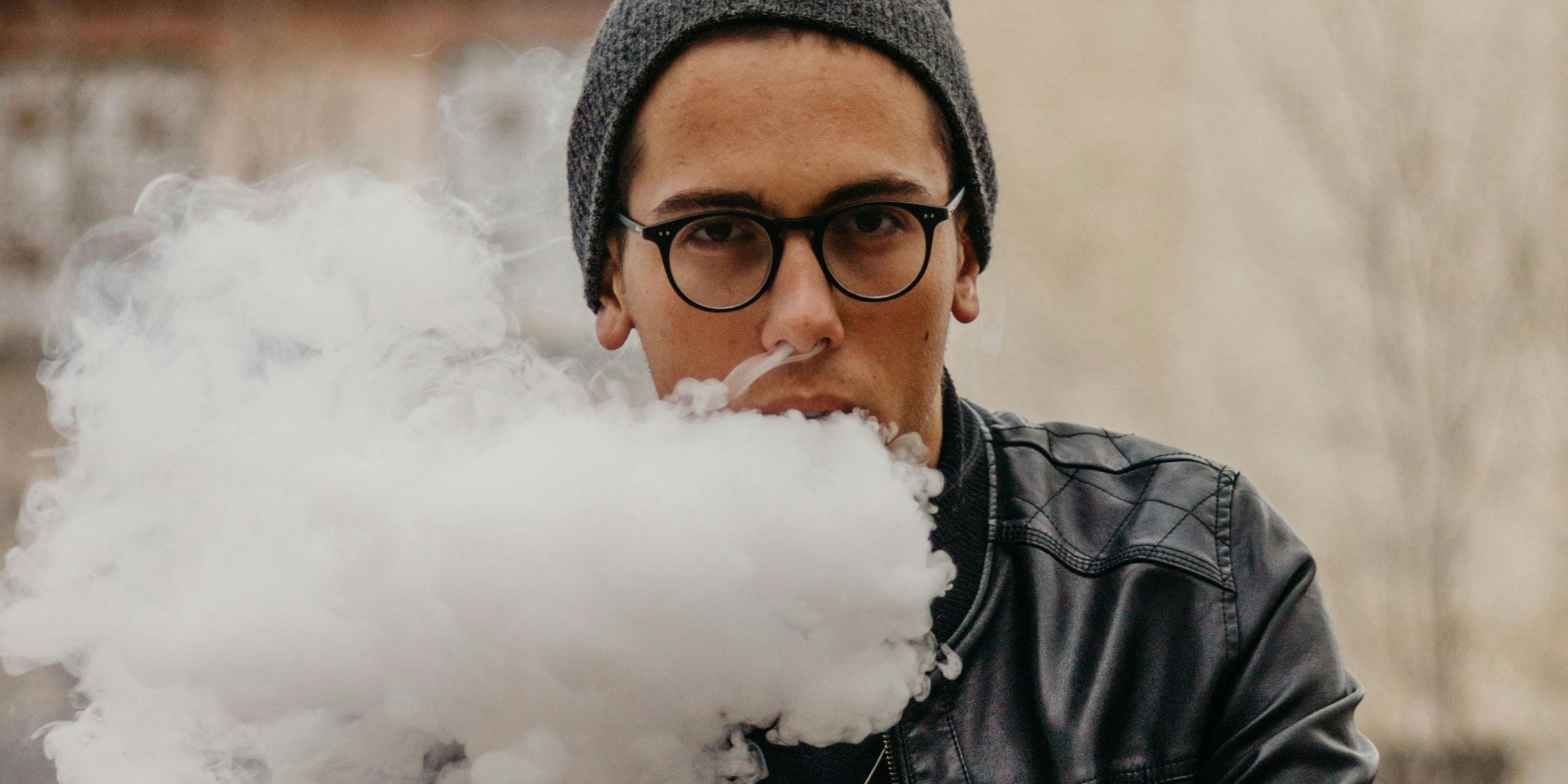 Teens vape cannabis using e-cigarettes. In this photo, a young man is shown blowing smoke.