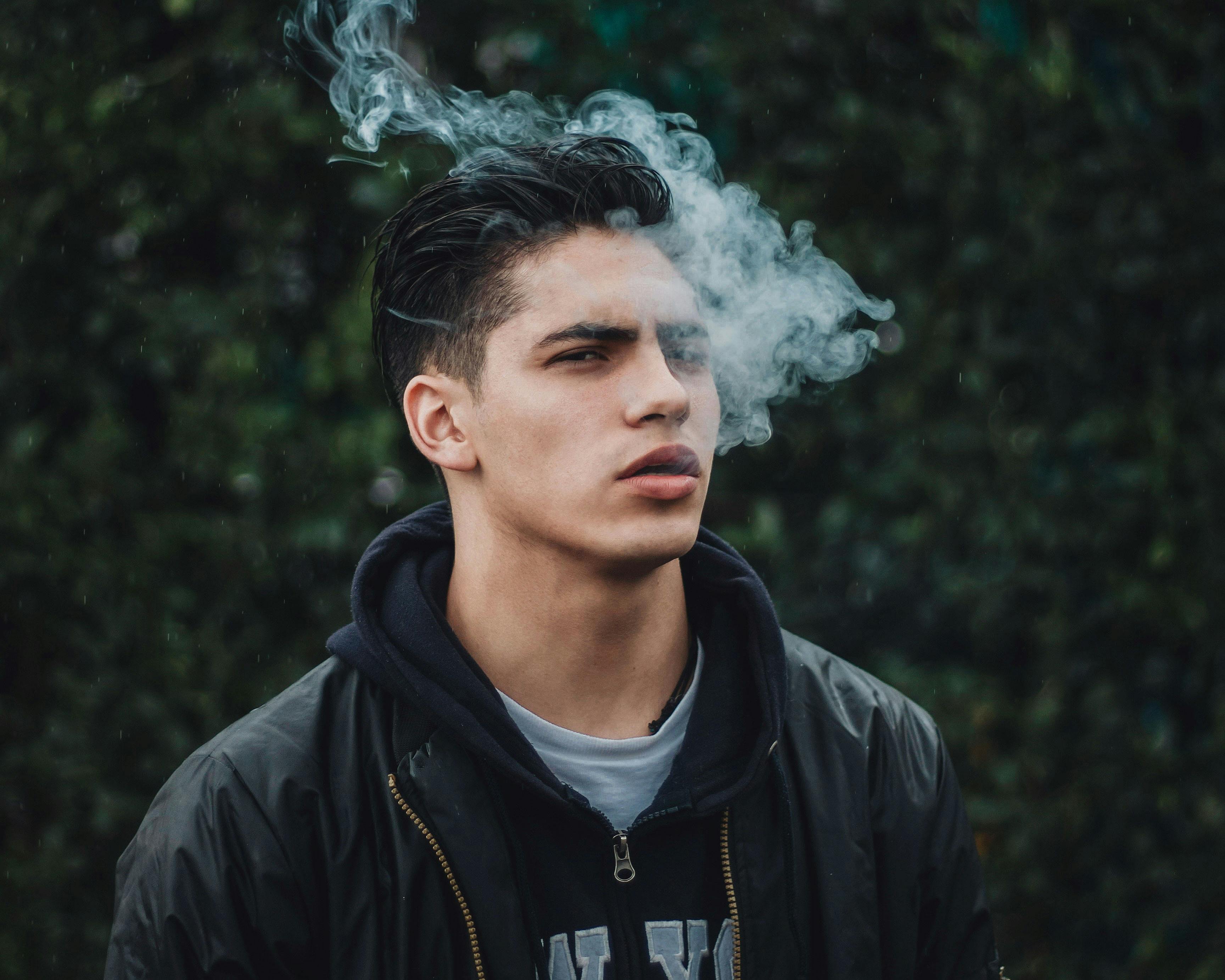 In this article, we feature the best cannabis strains for ADHD. Here, a man is shown exhaling smoke