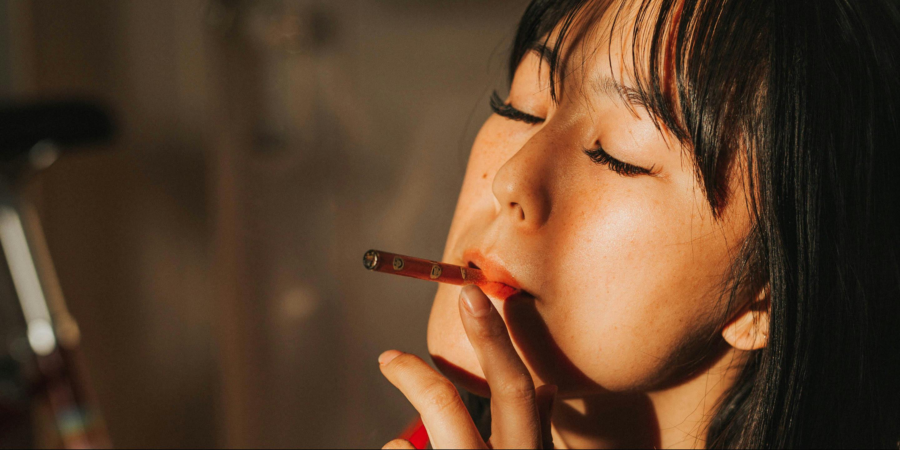 A woman smokes with her eyes closed. A woman smokes while sitting down. A new study cites that problematic behavior was not shown to increase in tandem with legalized cannabis laws.
