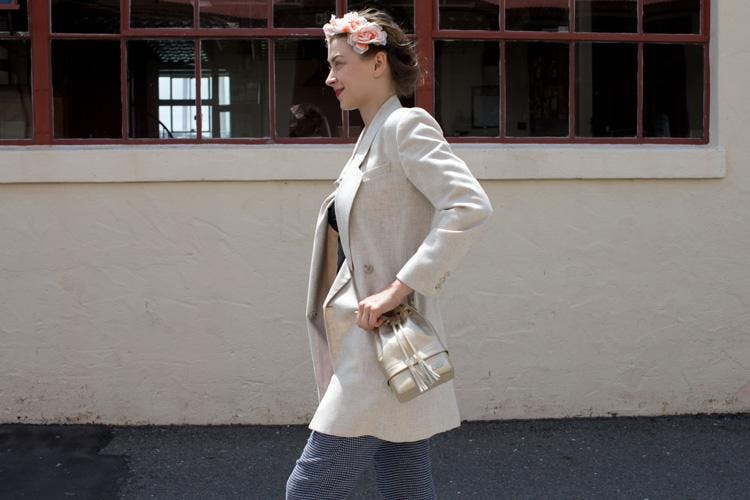 A woman with a floral headband and a cream blazer wears a stash bag that looks just like a designer handbag