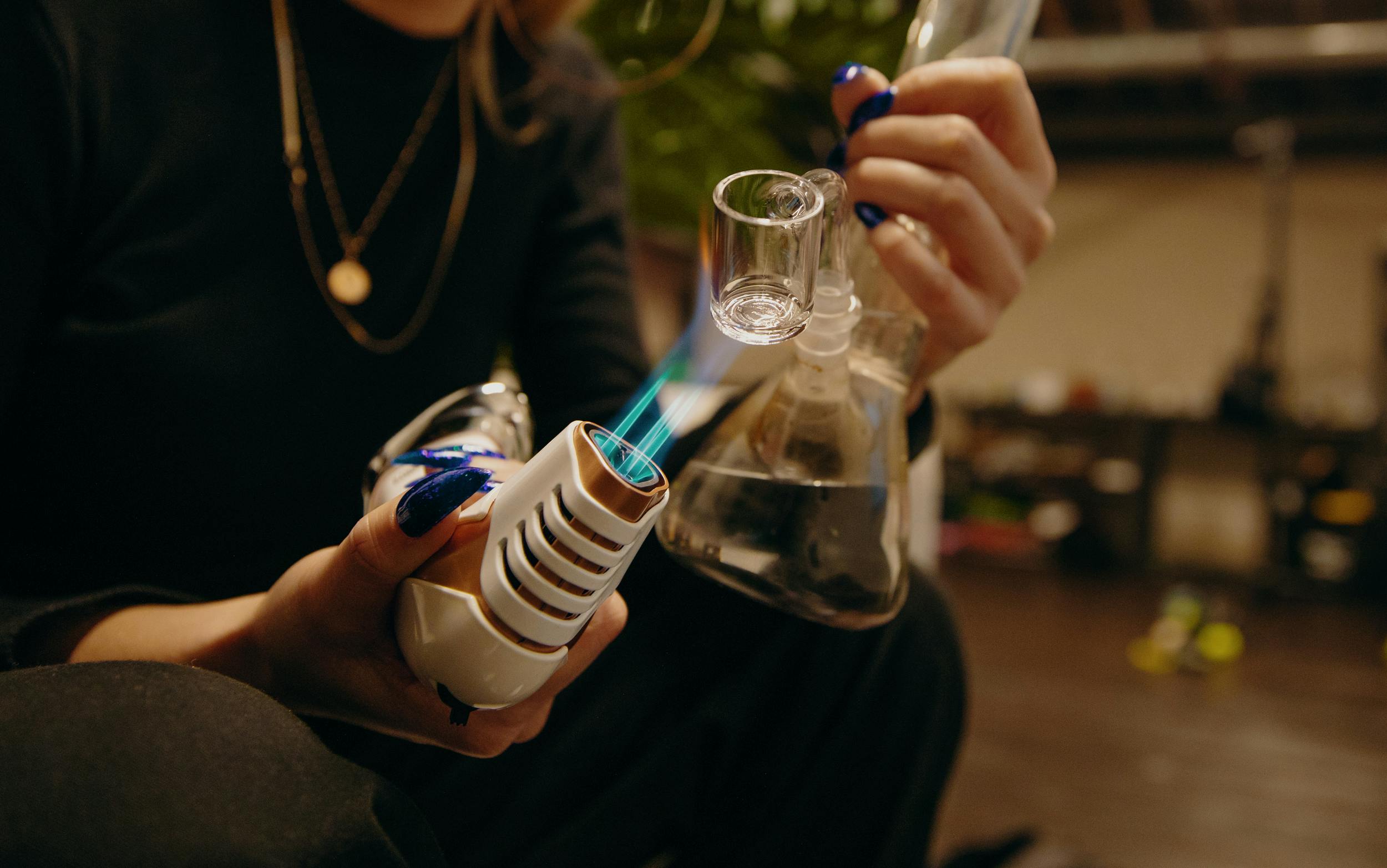 How to Smoke Hash Oil: A woman uses a butane torch to heat up a dab rig