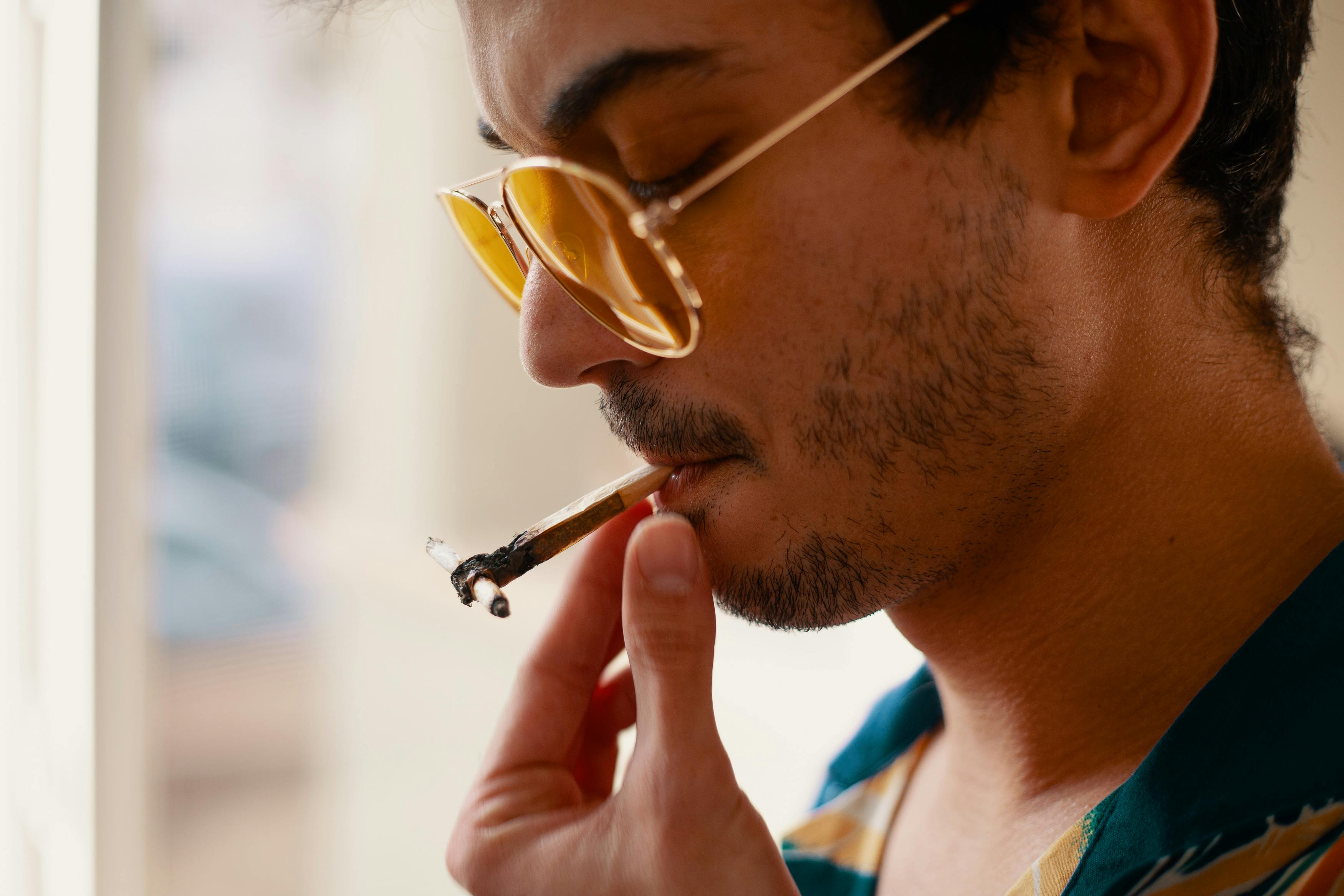How to Get High For The First Time: A man wearing sunglasses smokes a joint