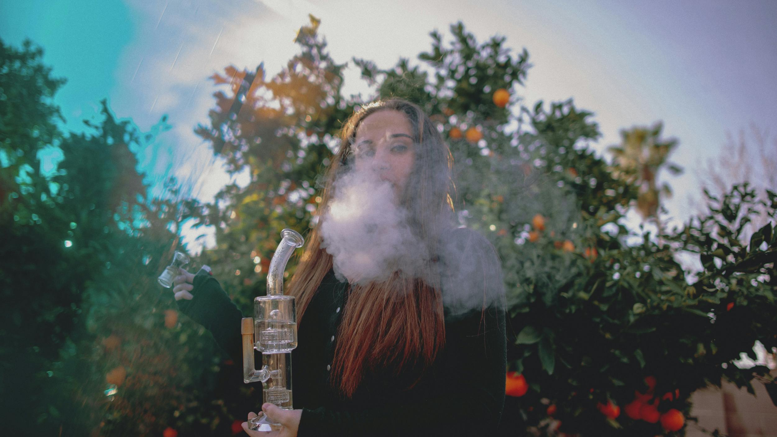 A woman smokes out of a pristine bong after using one of the best bong cleaners.