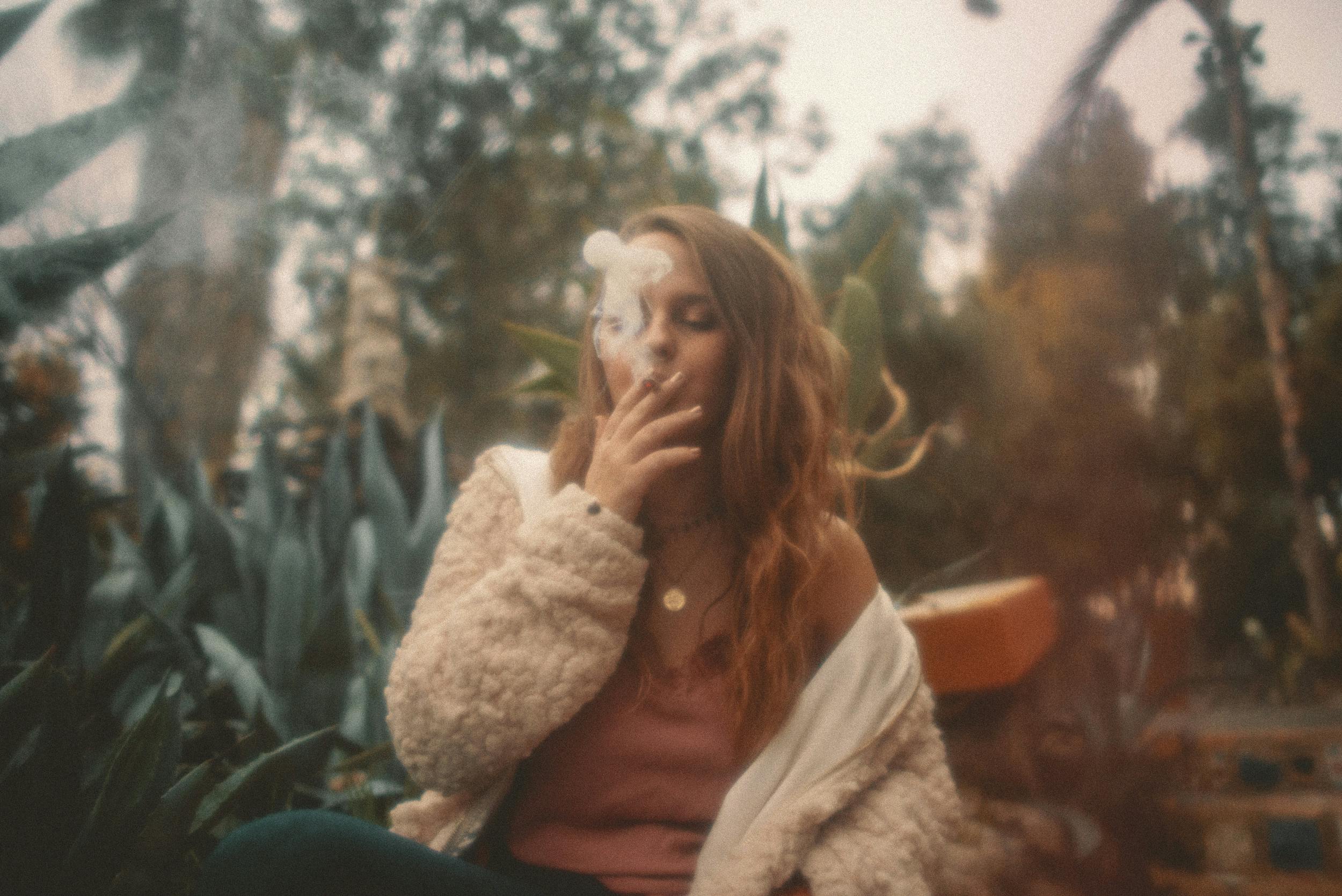 A woman smokes a joint rolled with one of the best kush strains