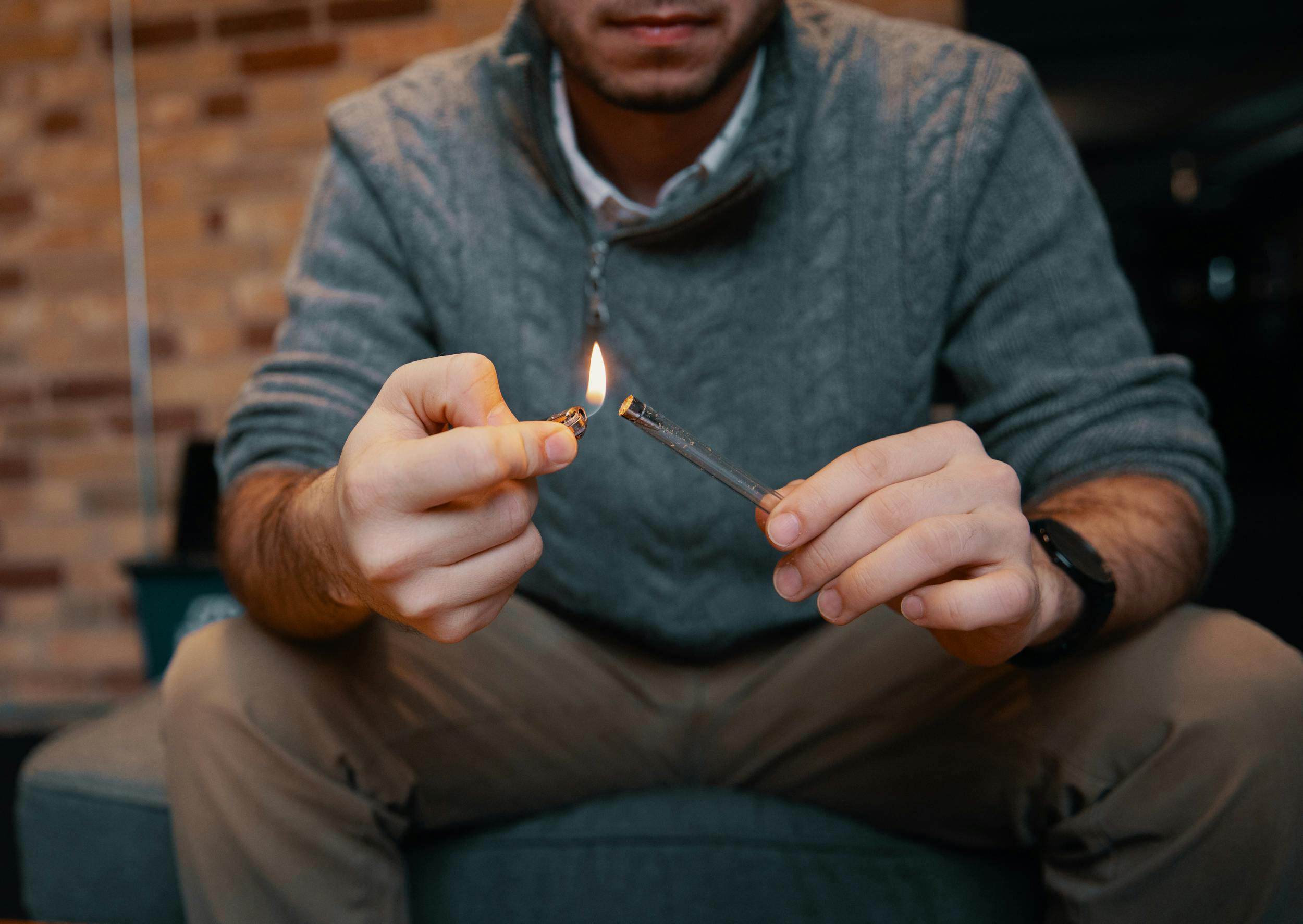 After learning how to make a pipe out of a pen, a man lights cannabis in a pen pipe